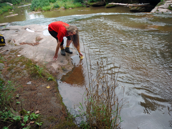 Karen wets her hiking rag in the river